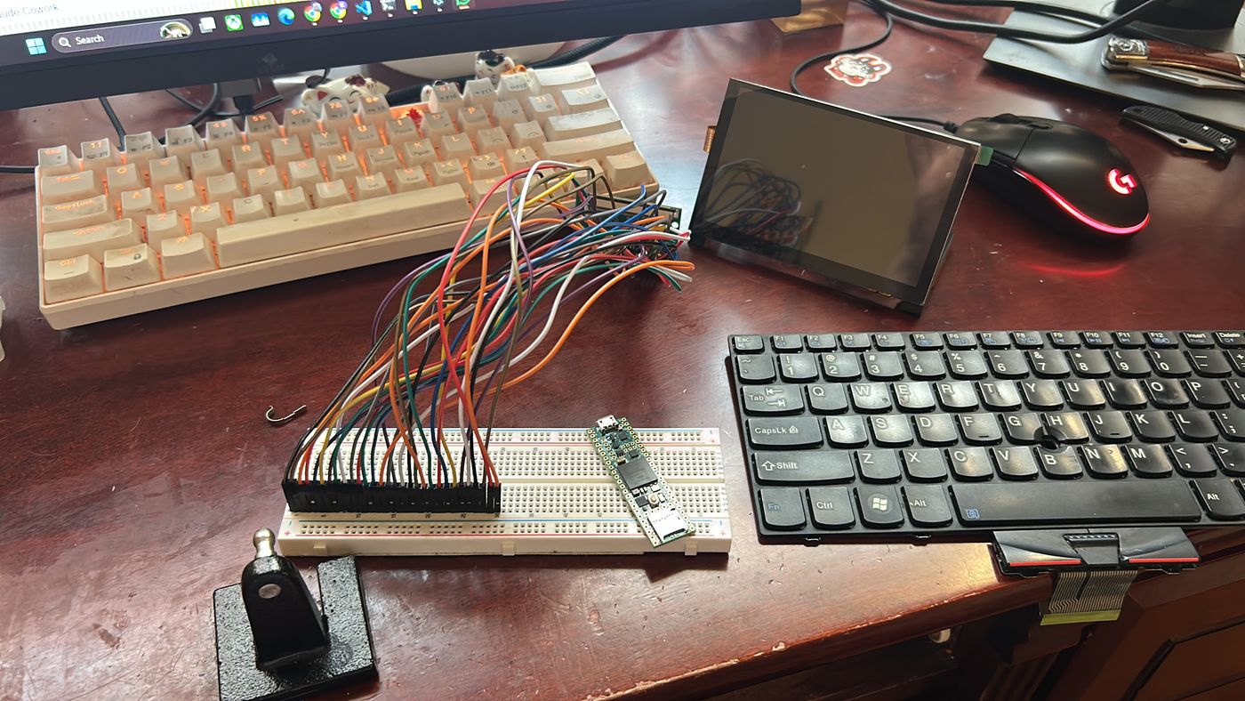 Breadboard with a Teensy, a bundle of jumper wires, the side display and the X100e keyboard on a desk